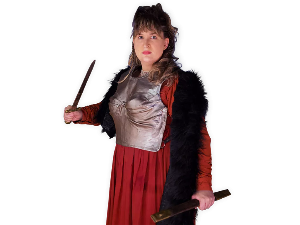 Viking Kindra holding a dagger and wearing a silver breastplate over her dress