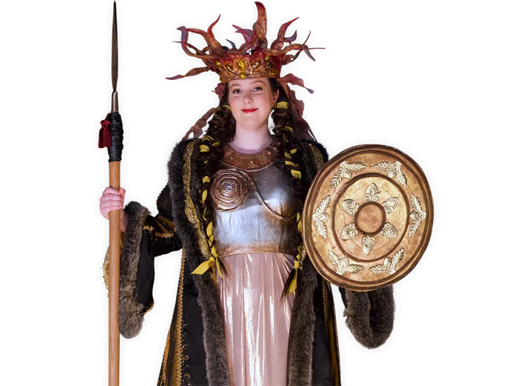 Viking queen Brita wearing an ornate crown and holding a shield and spear