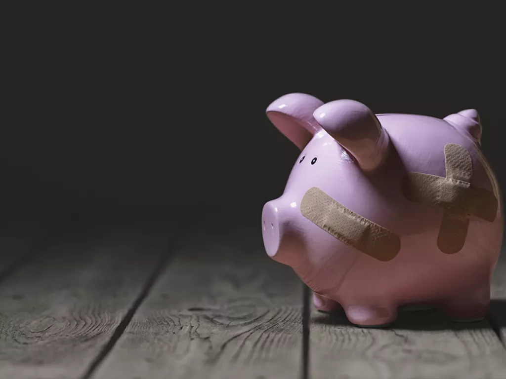 a piggy bank with adhesive bandages plastered to it