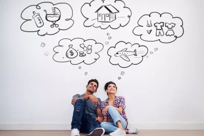 A couple with thought bubbles around their heads depicting a home, money, a baby, clothes, and an airplane