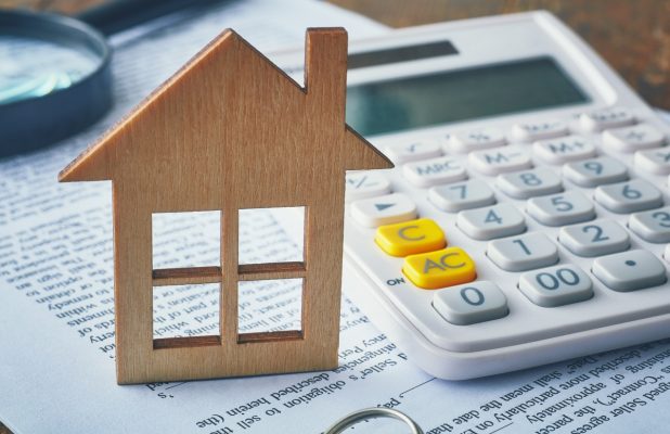 Wooden house next to calculator and tax forms