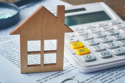 Wooden house next to calculator and tax forms