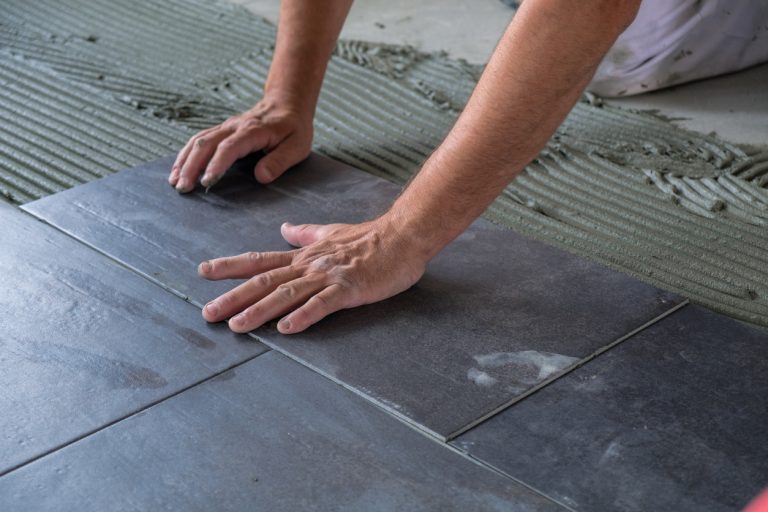 Worker installing ceramic floor tiles