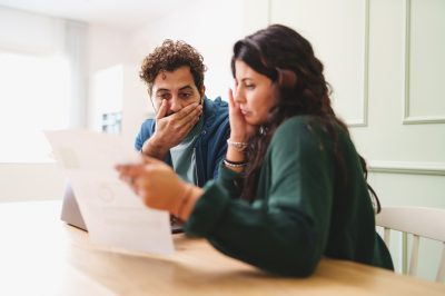 Young couple stressed at table looking at paper credit card statement