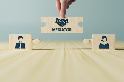 Two wooden blocks with someone holding a puzzle piece with "mediation" in between them