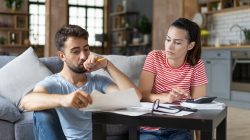 Frustrated concerned young couple calculating overspend budget, doing paperwork job at laptop, talking about financial problems, insurance, mortgage, fees, loan conditions, bankruptcy, economic inflation
