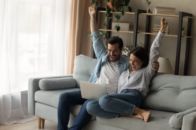 Young couple with arms in the air smiling after getting accepted into a debt relief program