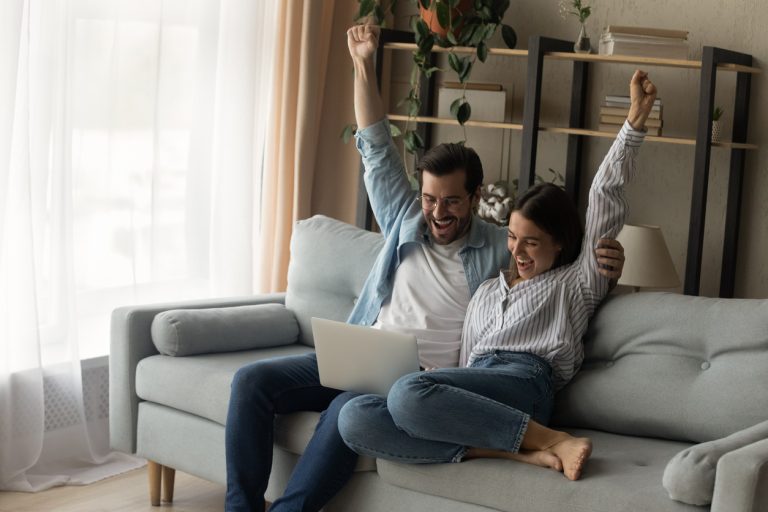 Young couple with arms in the air smiling after getting accepted into a debt relief program
