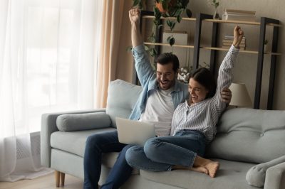 Young couple with arms in the air smiling after getting accepted into a debt relief program