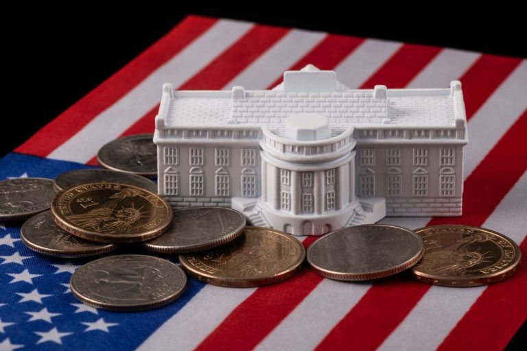 The symbolic residence of the US President, the White House, against the backdrop of the American flag and coins