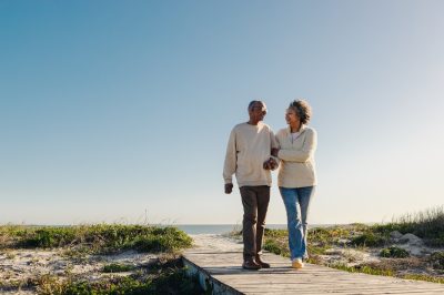 Senior couple walking on wooden beach path