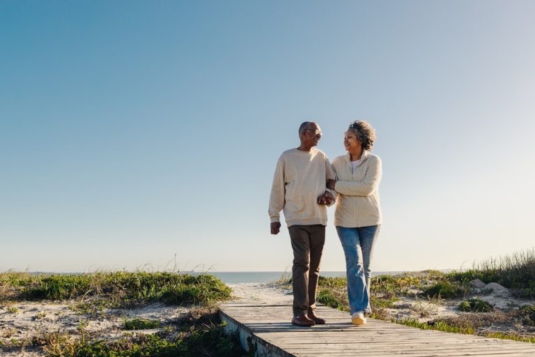 Senior couple walking on wooden beach path