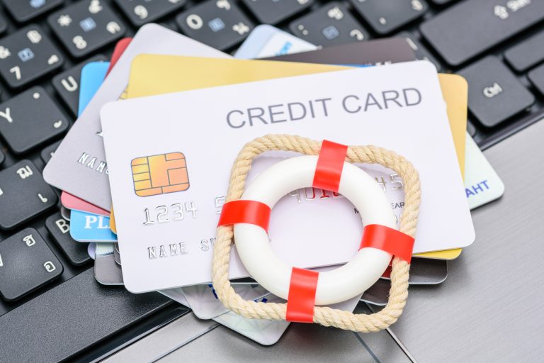 Credit cards on laptop with miniature life preserver. Nonprofit debt relief concept