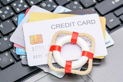 Credit cards on laptop with miniature life preserver. Nonprofit debt relief concept