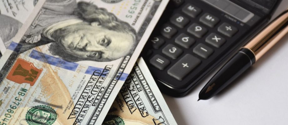 a few dollar bills, banknotes on a white background, with a golden pen and calculator, business concept