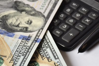 a few dollar bills, banknotes on a white background, with a golden pen and calculator, business concept