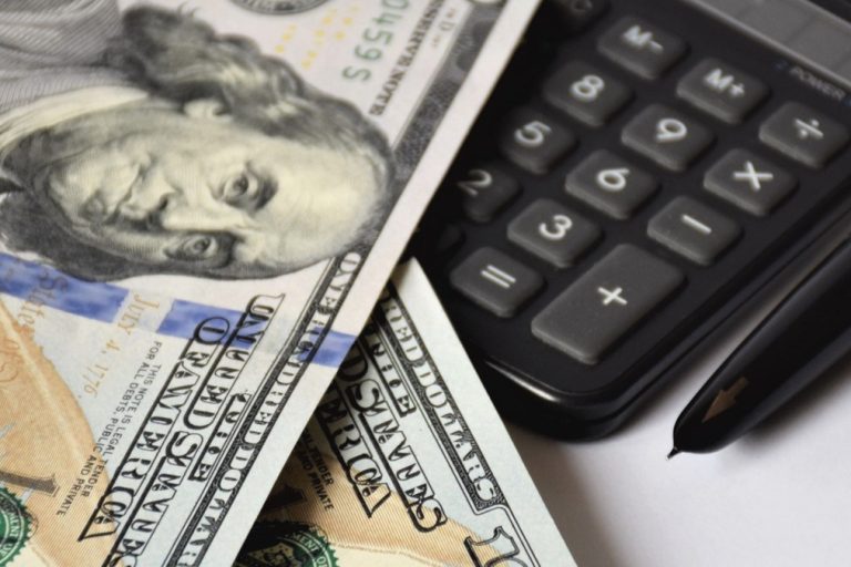 a few dollar bills, banknotes on a white background, with a golden pen and calculator, business concept