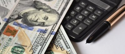 a few dollar bills, banknotes on a white background, with a golden pen and calculator, business concept