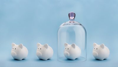 Piggybank protected under a glass dome on blue background