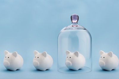 Piggybank protected under a glass dome on blue background