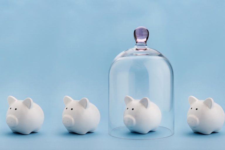 Piggybank protected under a glass dome on blue background