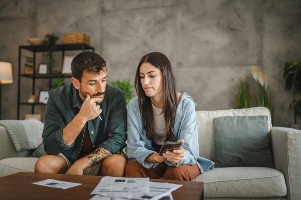 Adult serious couple sit and calculate their monthly domestic finances
