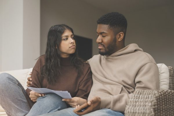 Young couple on couch wondering what will happen if they aren't able to make credit card payment
