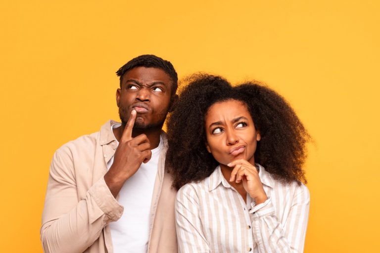 Pensive black couple in casual wear on yellow backdrop