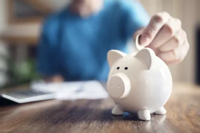a person puts a coin into a piggy bank