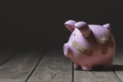 Broken piggy bank with band aid bandage or plaster finance background