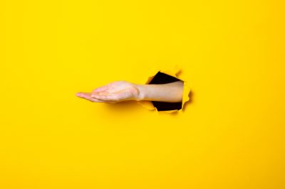 Opened male hand, palm up on a yellow background. Debt collection concept