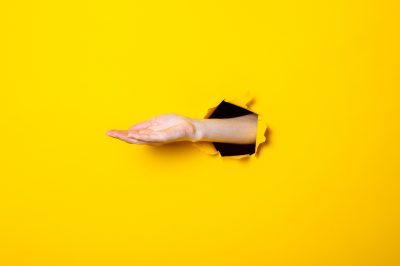 Opened male hand, palm up on a yellow background. Debt collection concept