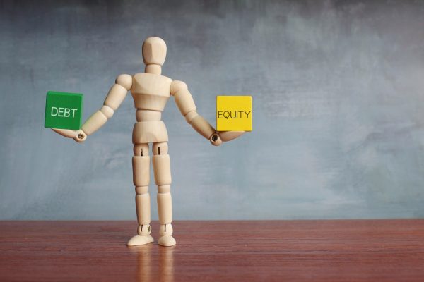 Debt and equity balance concept. Figurine holding cubes.