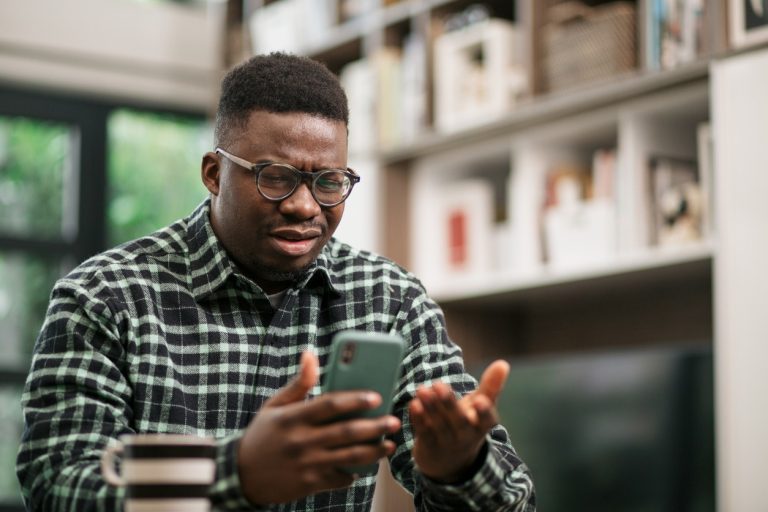 Man looking at ringing phone confused